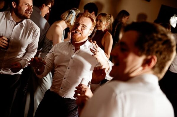 Wedding guests celebrating and dancing at Cornwall wedding reception