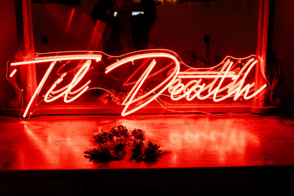Til Death neon sign glowing red at Wonwood Barton wedding venue Tavistock Devon