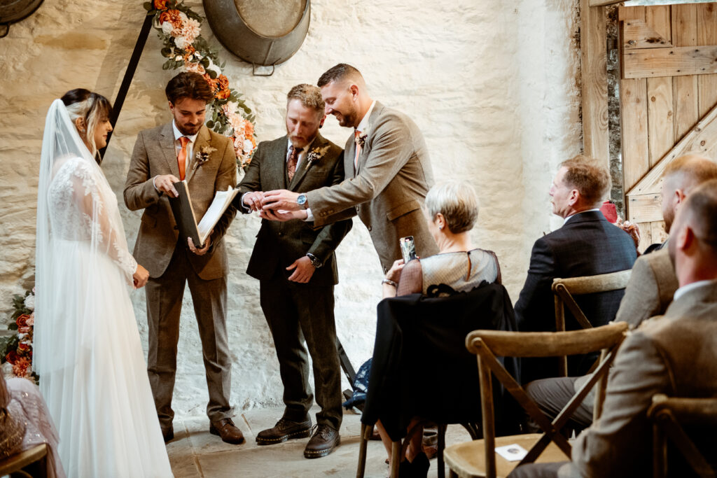 Ring exchange over tattooed hands at Wonwood Barton eclectic wedding Tavistock