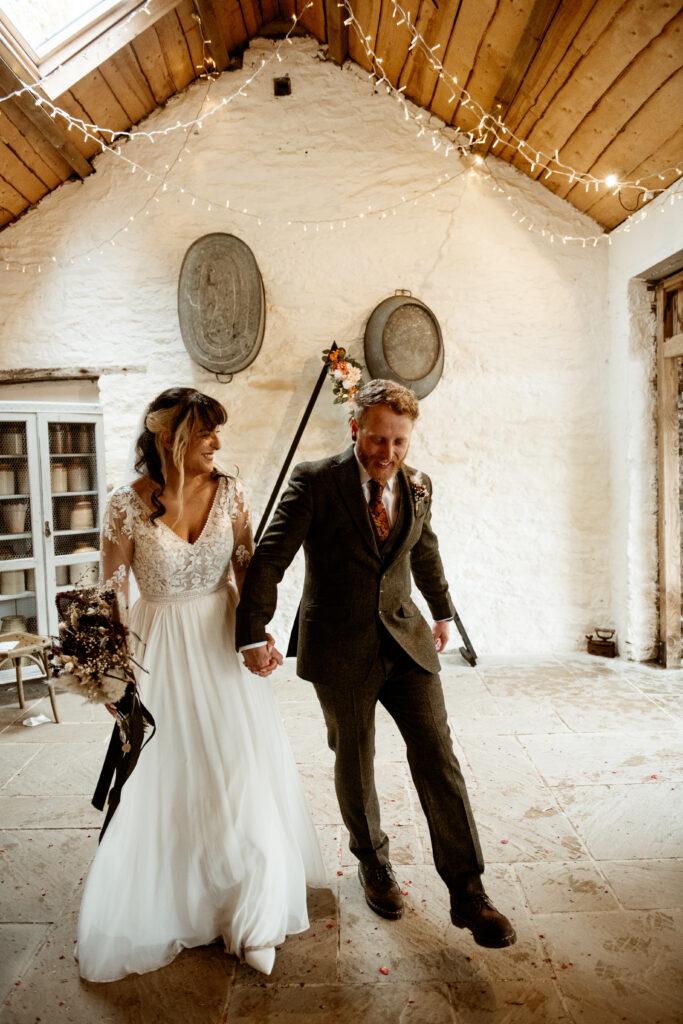 Couple walking under crossed swords at Wonwood Barton wedding ceremony Tavistock Devon