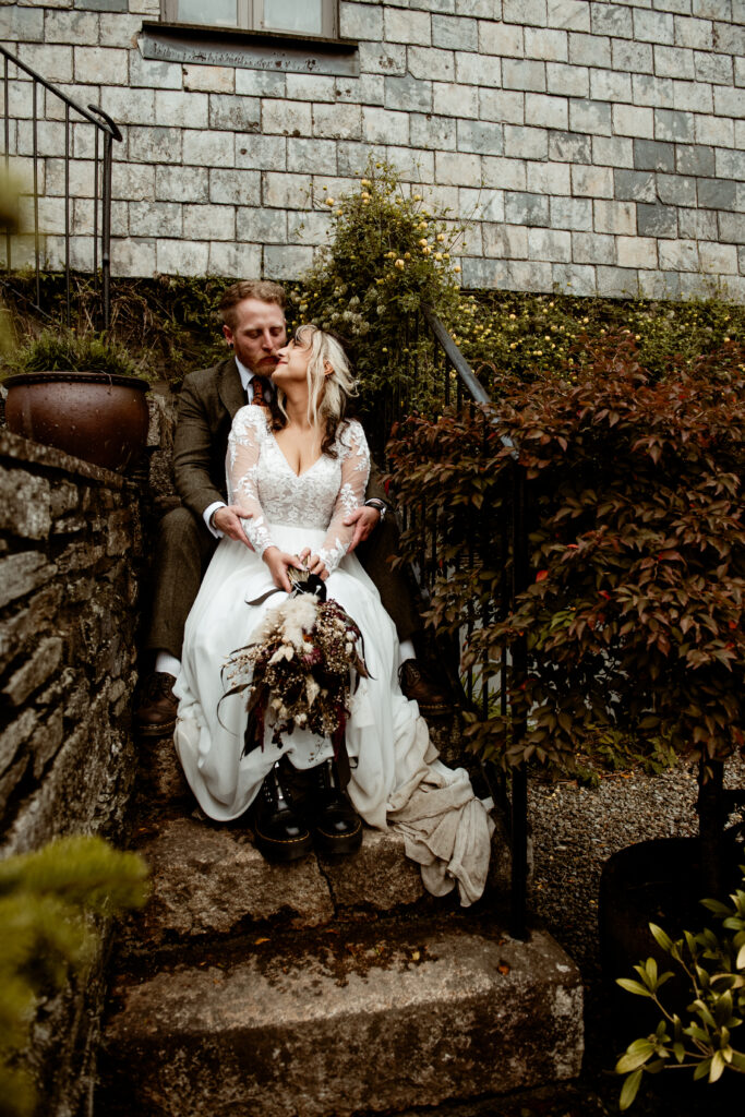 Bride in lace dress and Doc Martens sitting on mossy steps at Wonwood Barton Tavistock