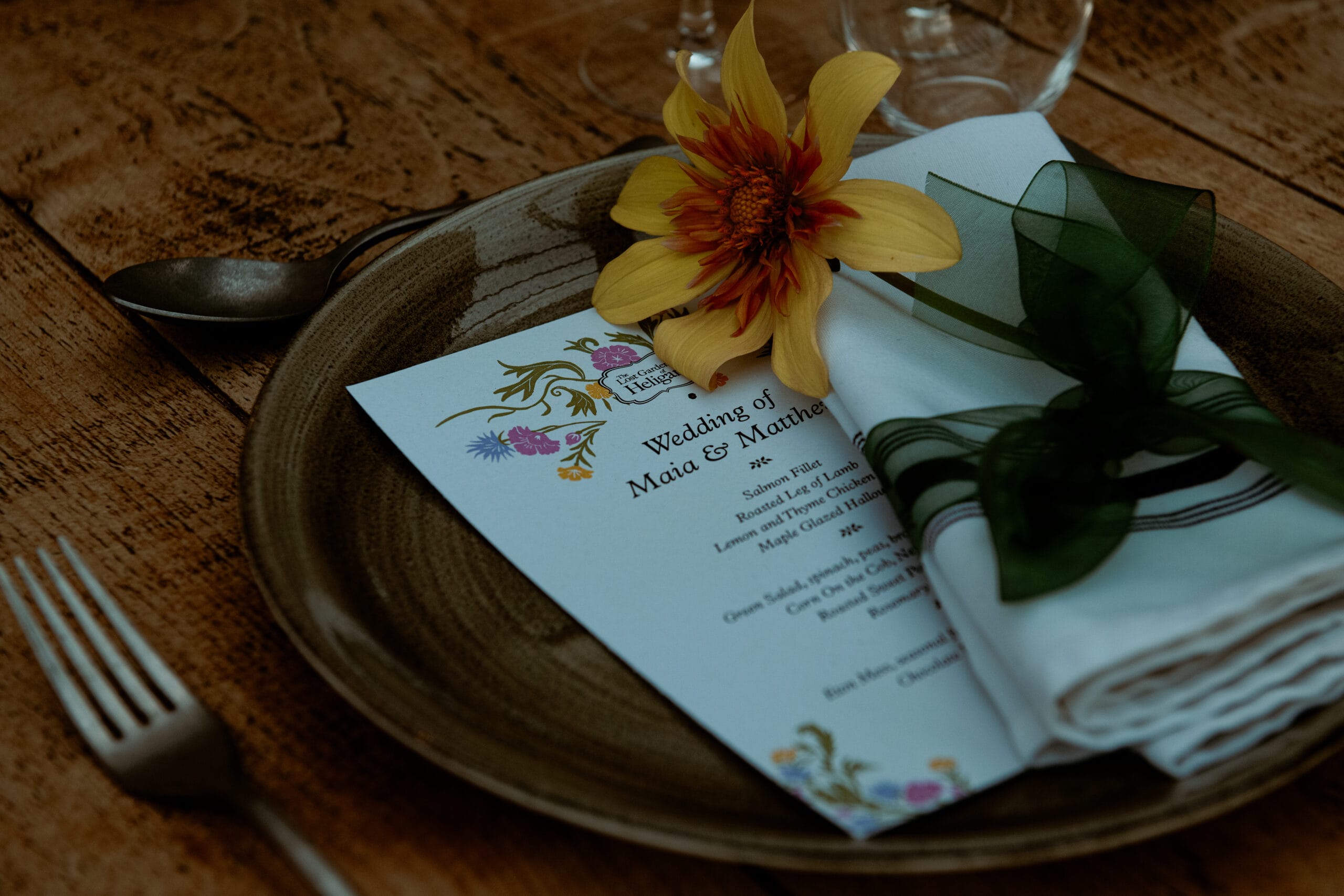 Wedding order of service with yellow flower on slate at Lost Gardens of Heligan Cornwall wedding