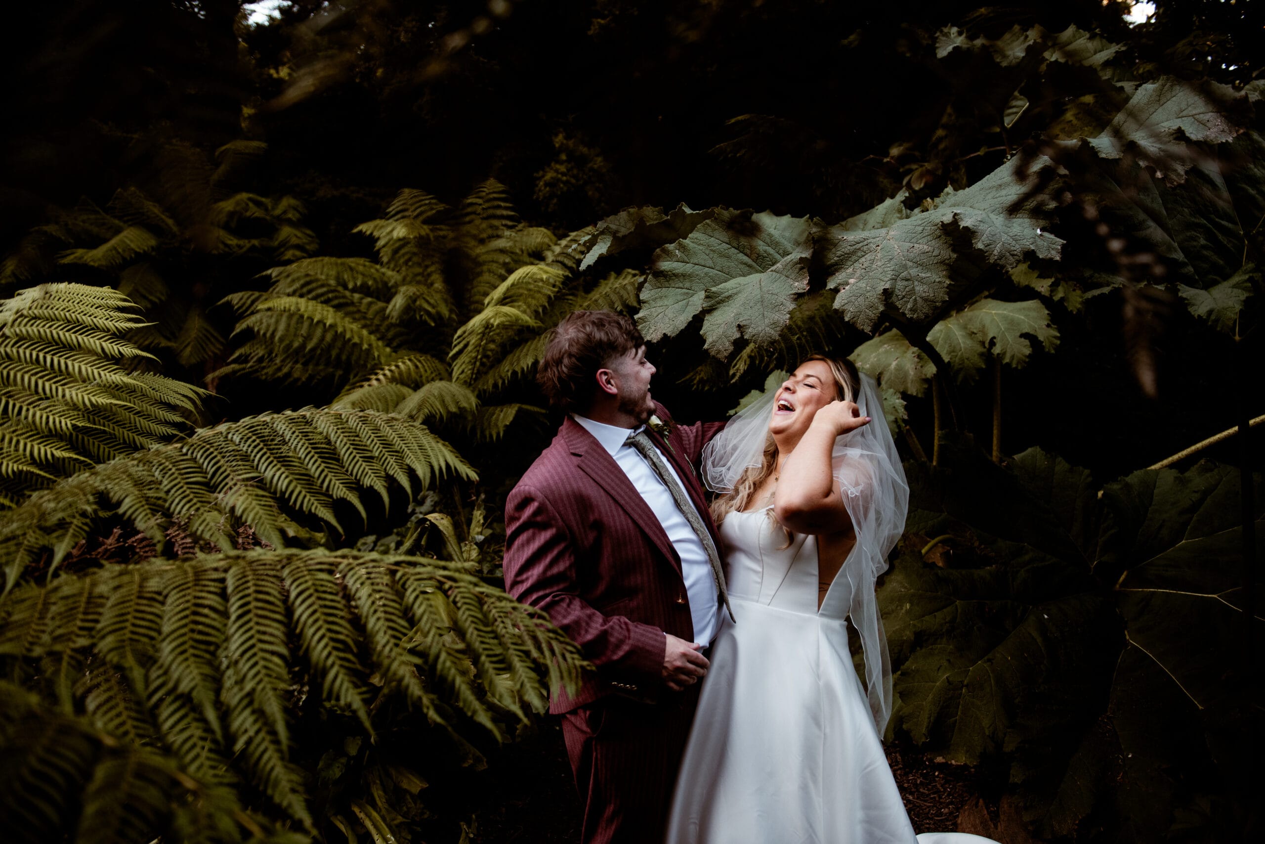 Bride and groom laughing together in the fern garden at Lost Gardens of Heligan wedding