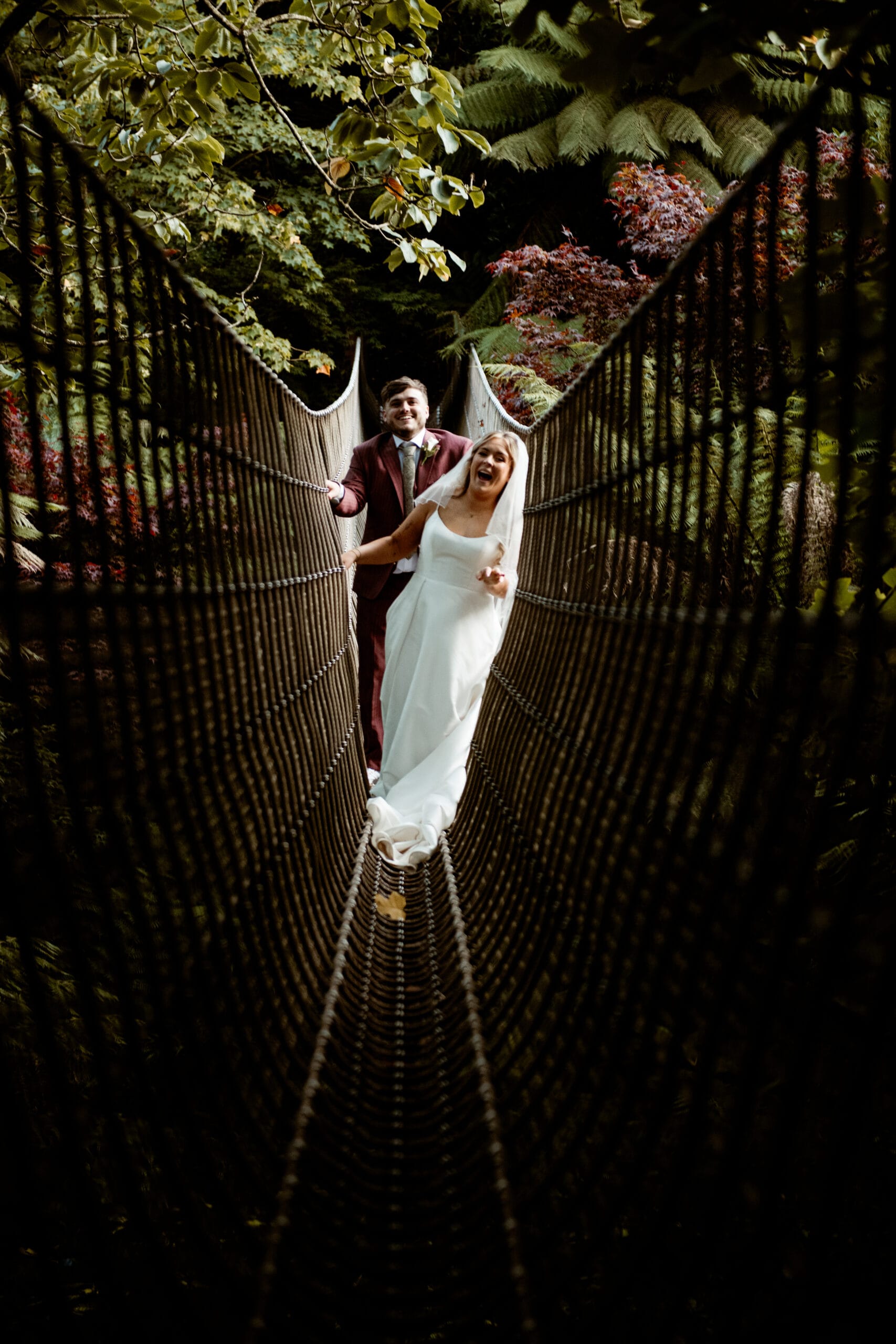 Bride in white gown on rope bridge at Lost Gardens of Heligan Cornwall wedding