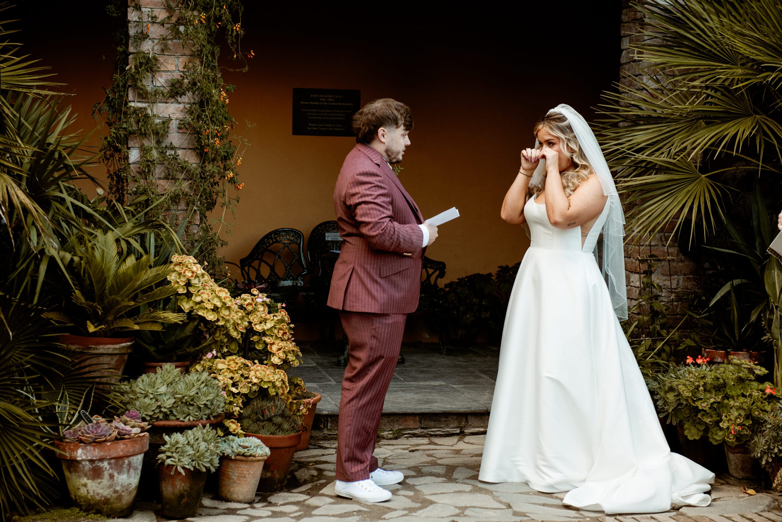 Bride and groom standing together in front of Italian Garden terracotta wall at Heligan Cornwall