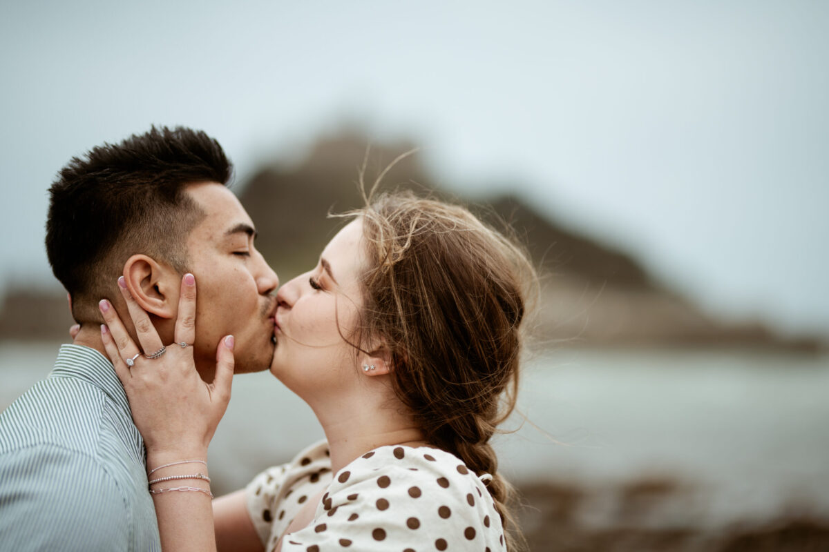 Newly engaged couple kissing with St Michael's Mount in the background, Marazion, Cornwall — engagement photographer