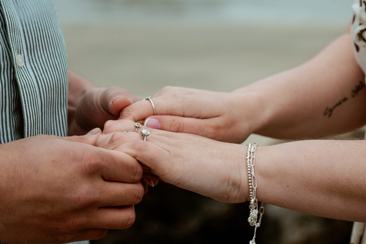 Close-up of Tay sliding the engagement ring onto Beth's finger at Marazion, Cornwall